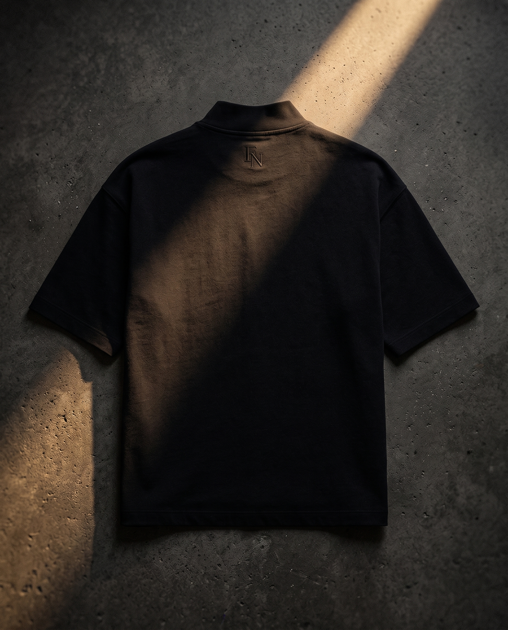 Playera negra FORM 01 vista posterior con monograma FN sobre concreto